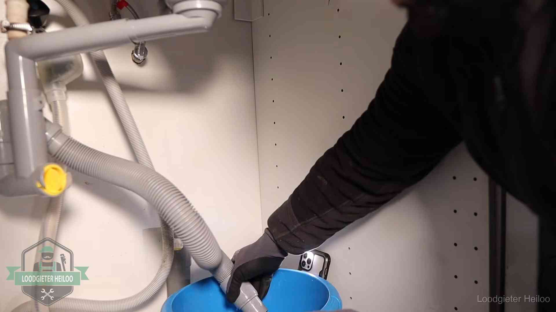 Afvoerslang loopt leeg in een emmer onder de gootsteen in Heiloo, een klus die je zelf kunt doen