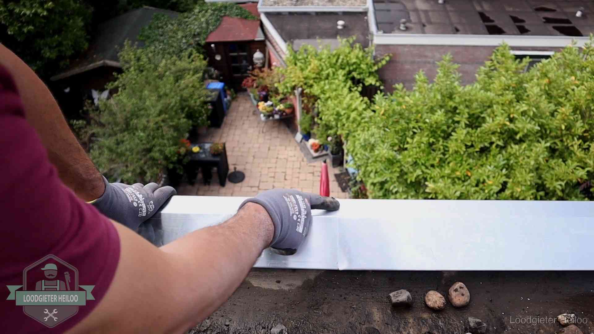 Vakman plaatst een daktrim op de dakrand van een woning in Heiloo