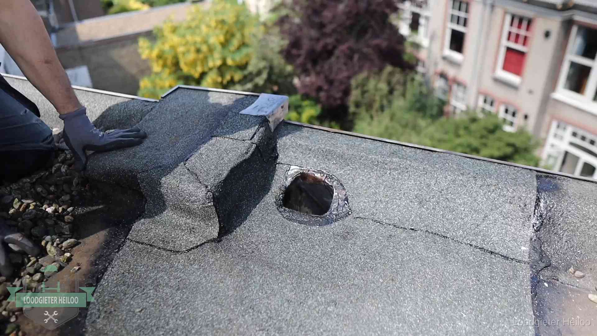 Loodgieter inspecteert een beschadigd bitumen plat dak tijdens een daklekkage-inspectie in Heiloo