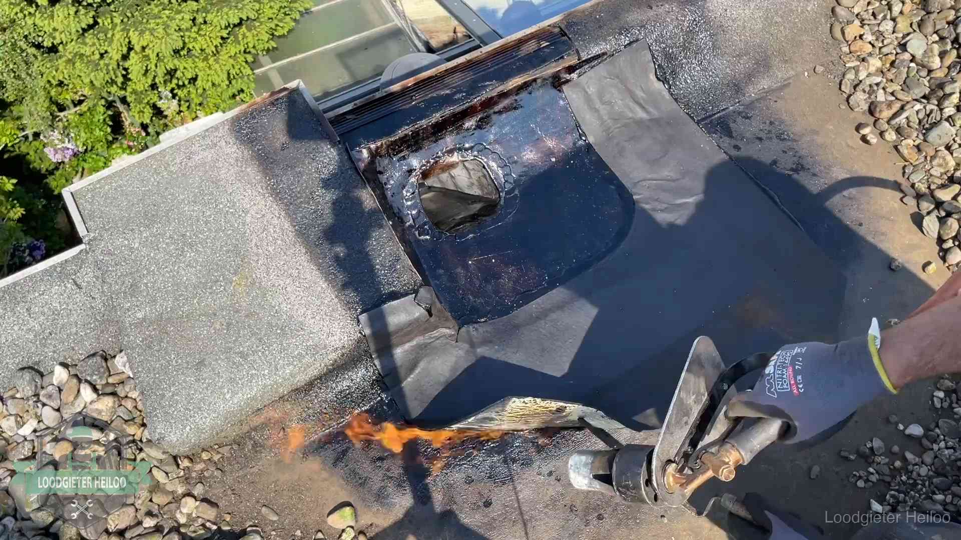 Dakdekker brandt bitumen rond een doorvoer tijdens een daklekkage-reparatie in Heiloo