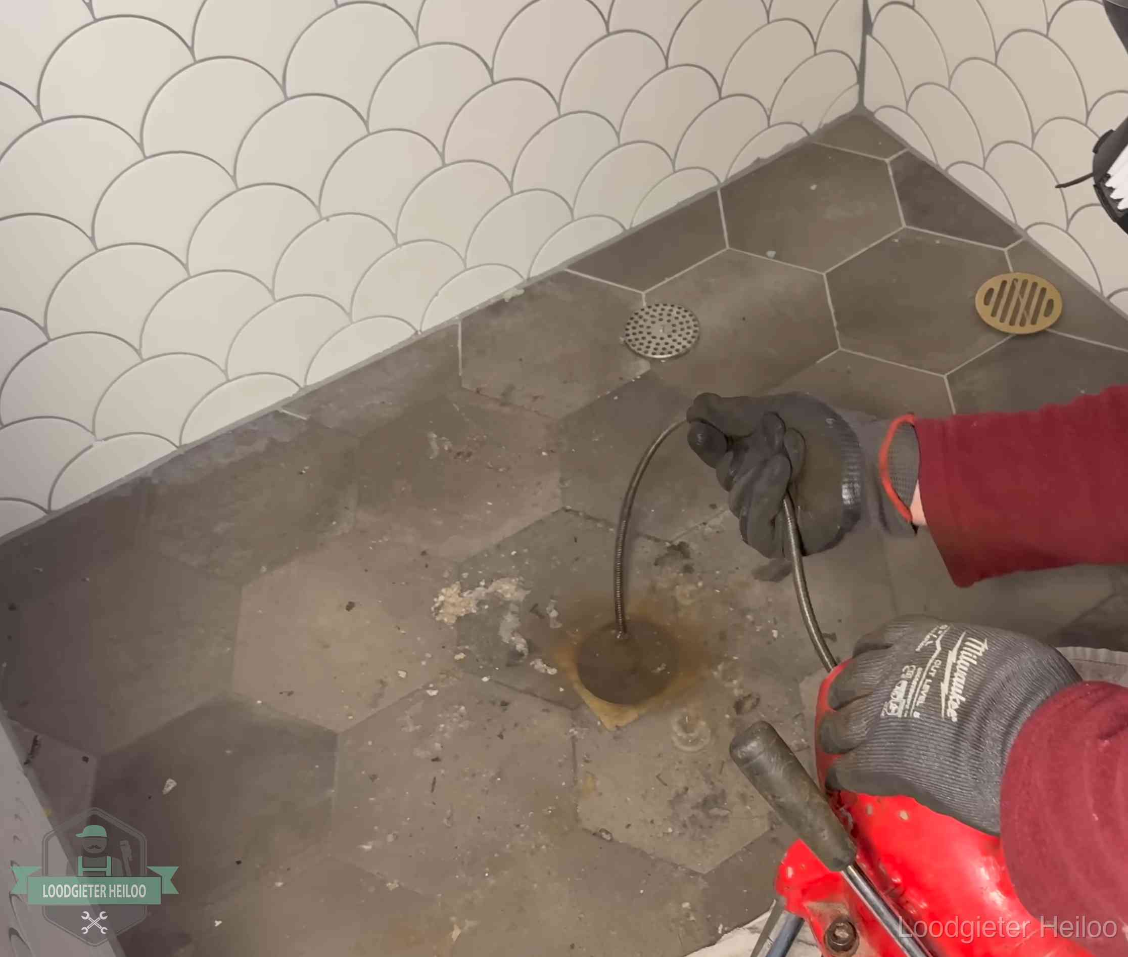 Ontstoppingsveer gaat in een geopend doucheputje in Heiloo waar het water omhoogkwam