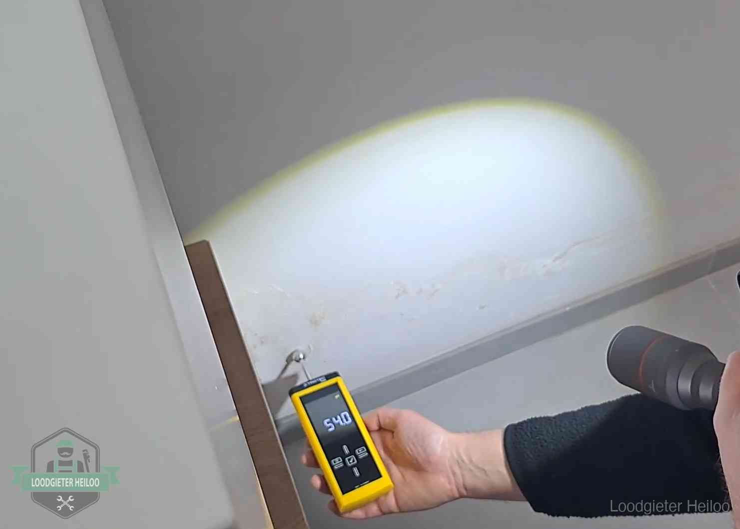 Vochtmeter tegen een natte wand met lekkagesporen in Heiloo
