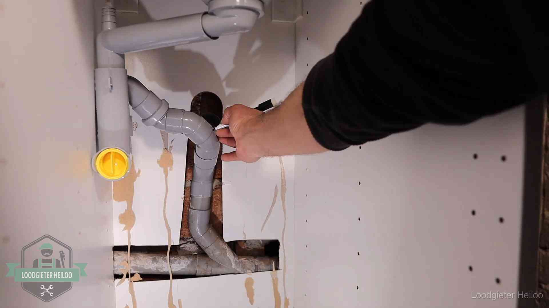 Loodgieter voor verhuurders en bedrijven in Heiloo Loodgieter markeert een pvc-afvoerbuis onder een gootsteen in Heiloo