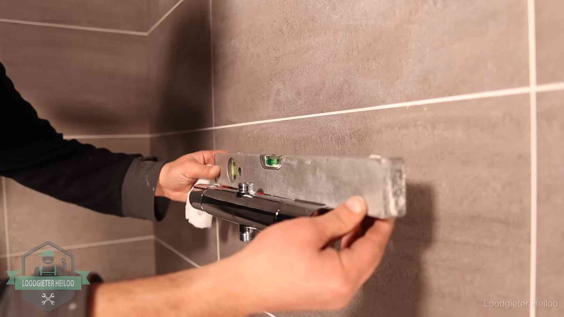 Loodgietersbedrijf voor sanitair in Heiloo Loodgieter lijnt een douchekraan uit met een waterpas in een woning in Heiloo