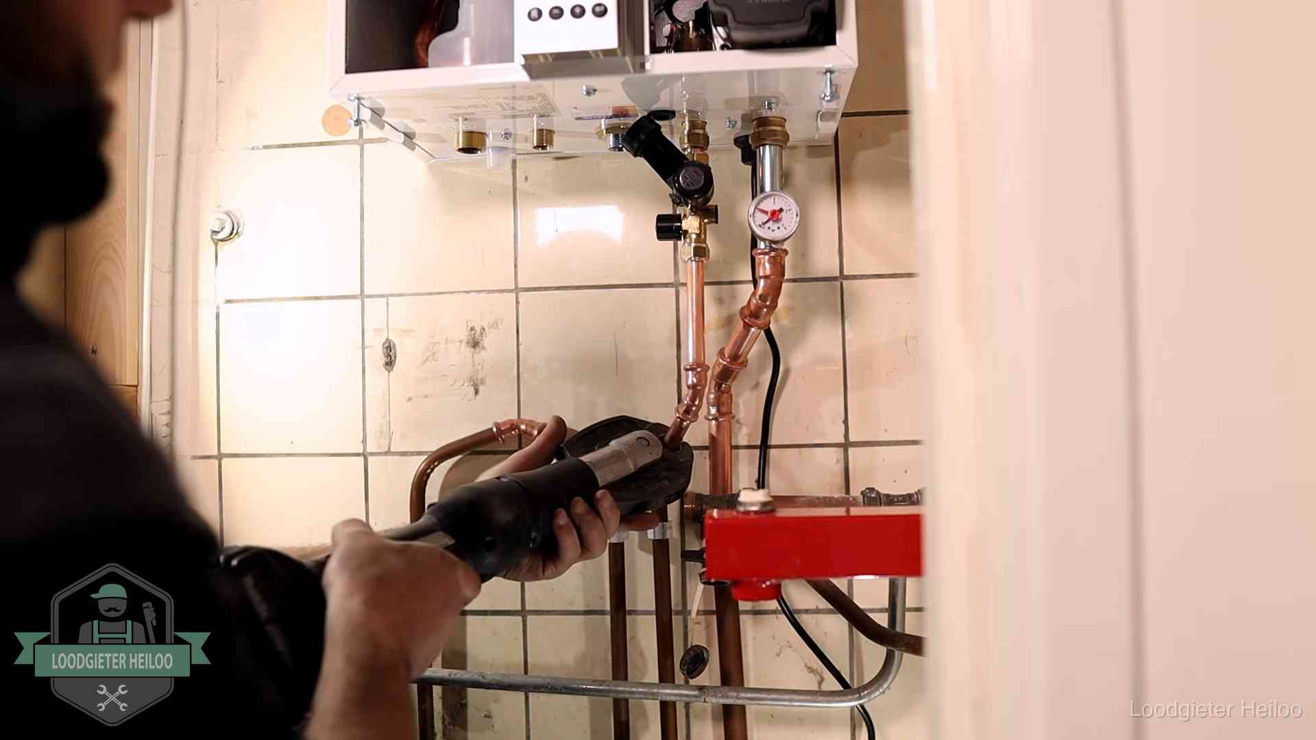 Monteur werkt aan de leidingen onder een cv-ketel in Heiloo