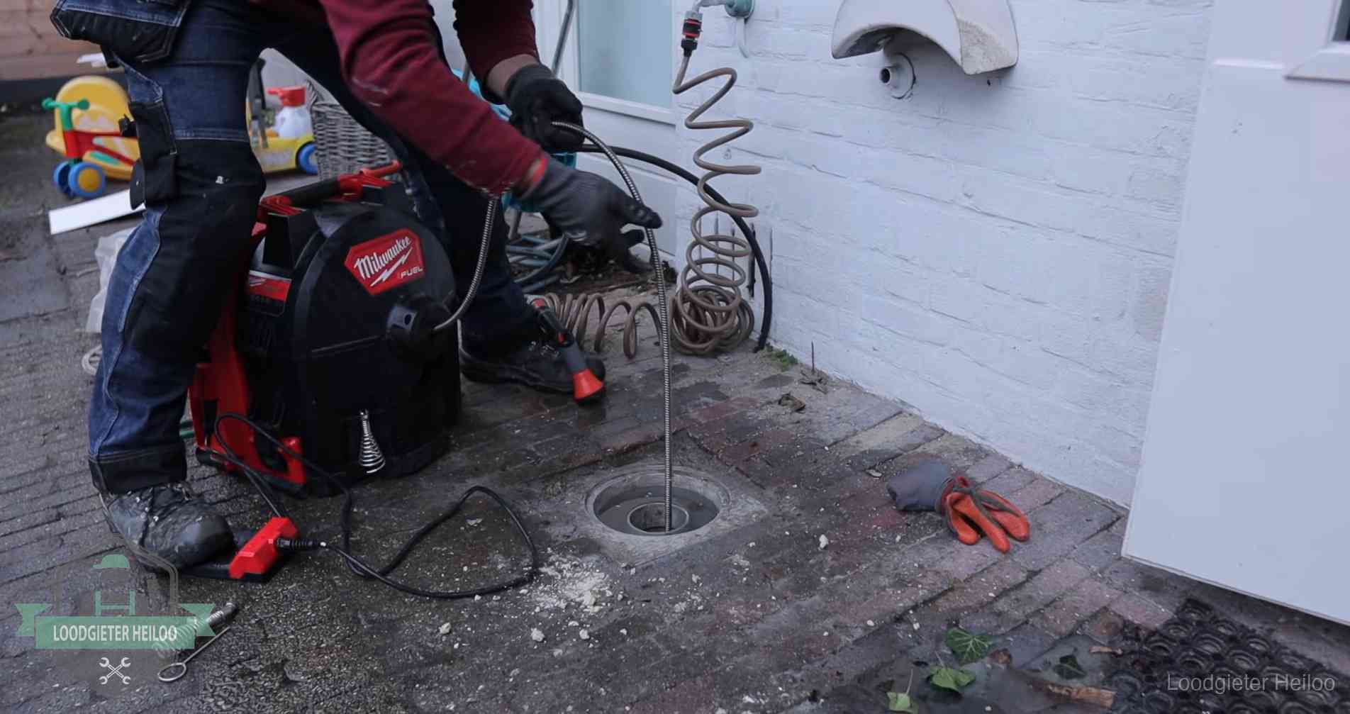 Ontstoppingsputje in de bestrating naast de gevel van een woning in Heiloo