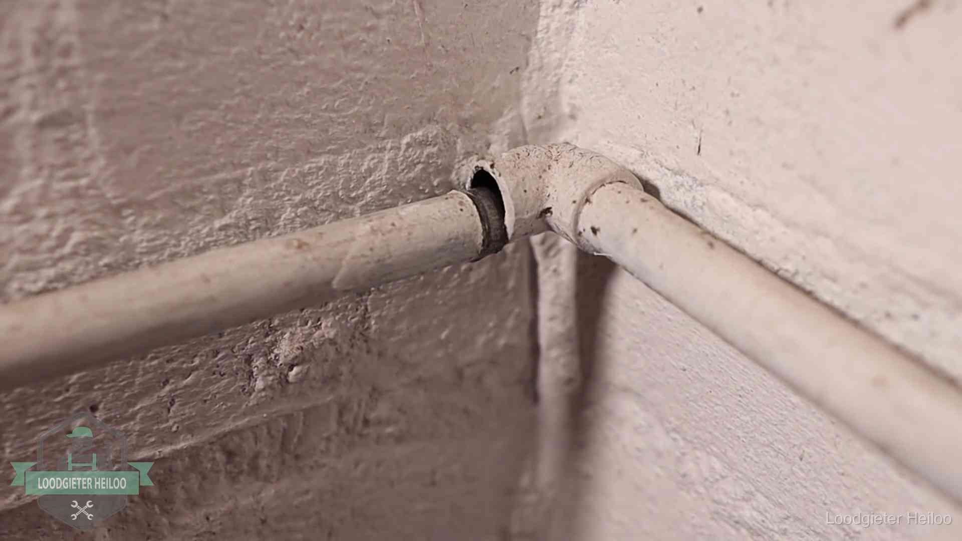 Oude geverfde waterleiding met een losliggende fitting in een woning in Heiloo
