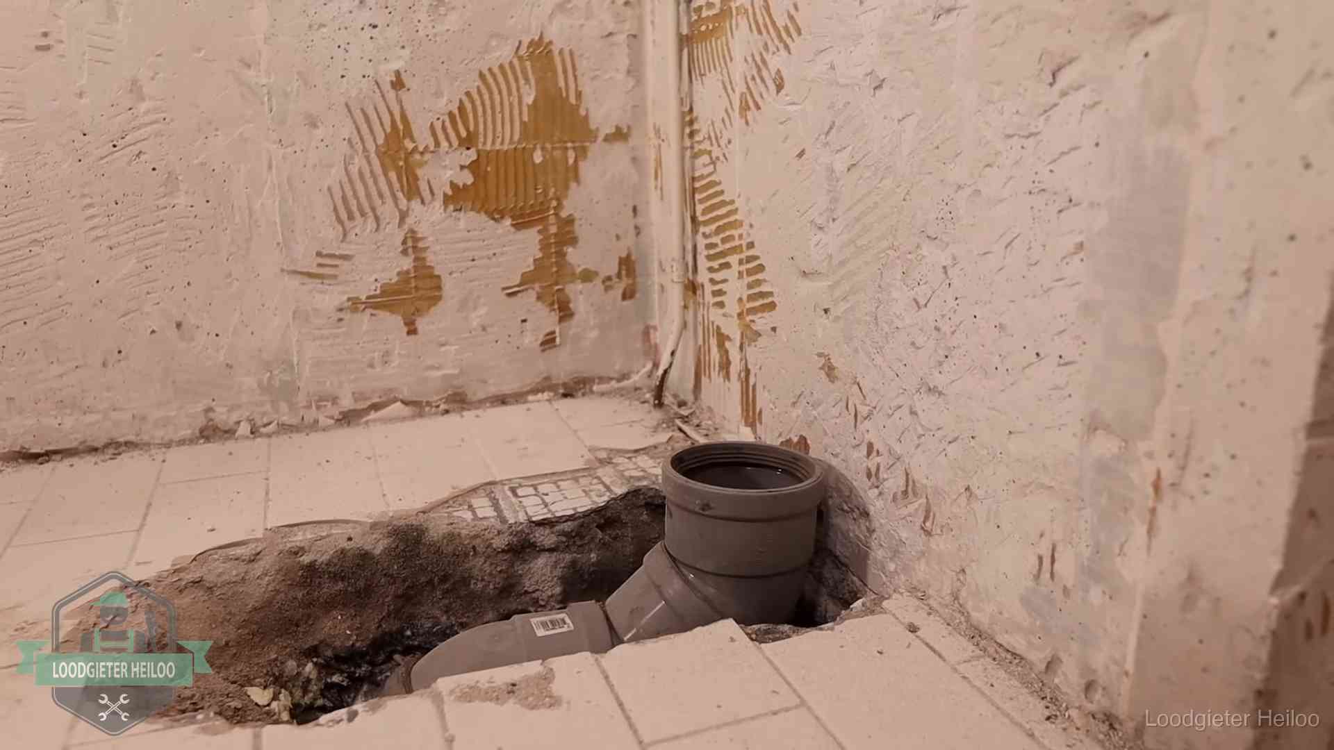 Opengebroken vloer met een nieuwe pvc-rioolbocht in een gegraven sleuf in Heiloo