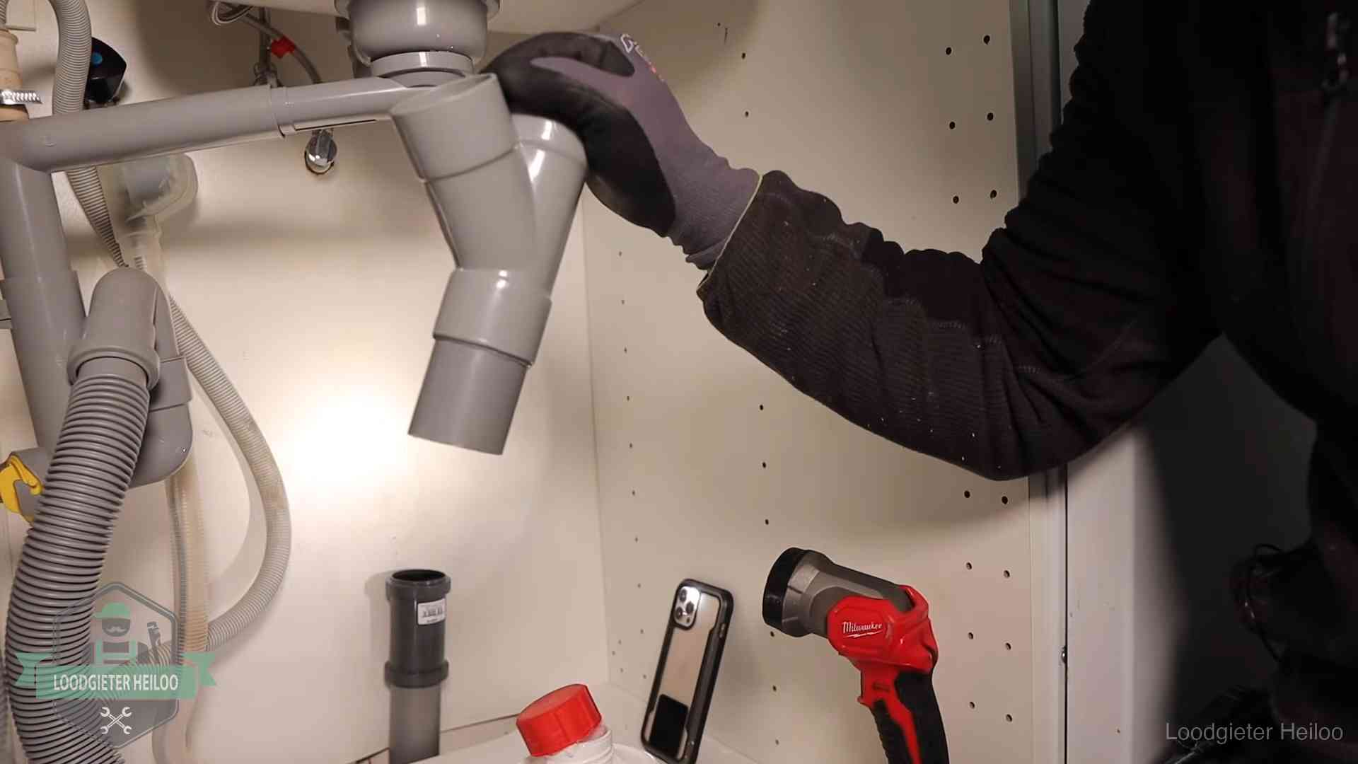 Loodgieter demonteert het sifon- en afvoerwerk onder een gootsteen in Heiloo bij stankklachten