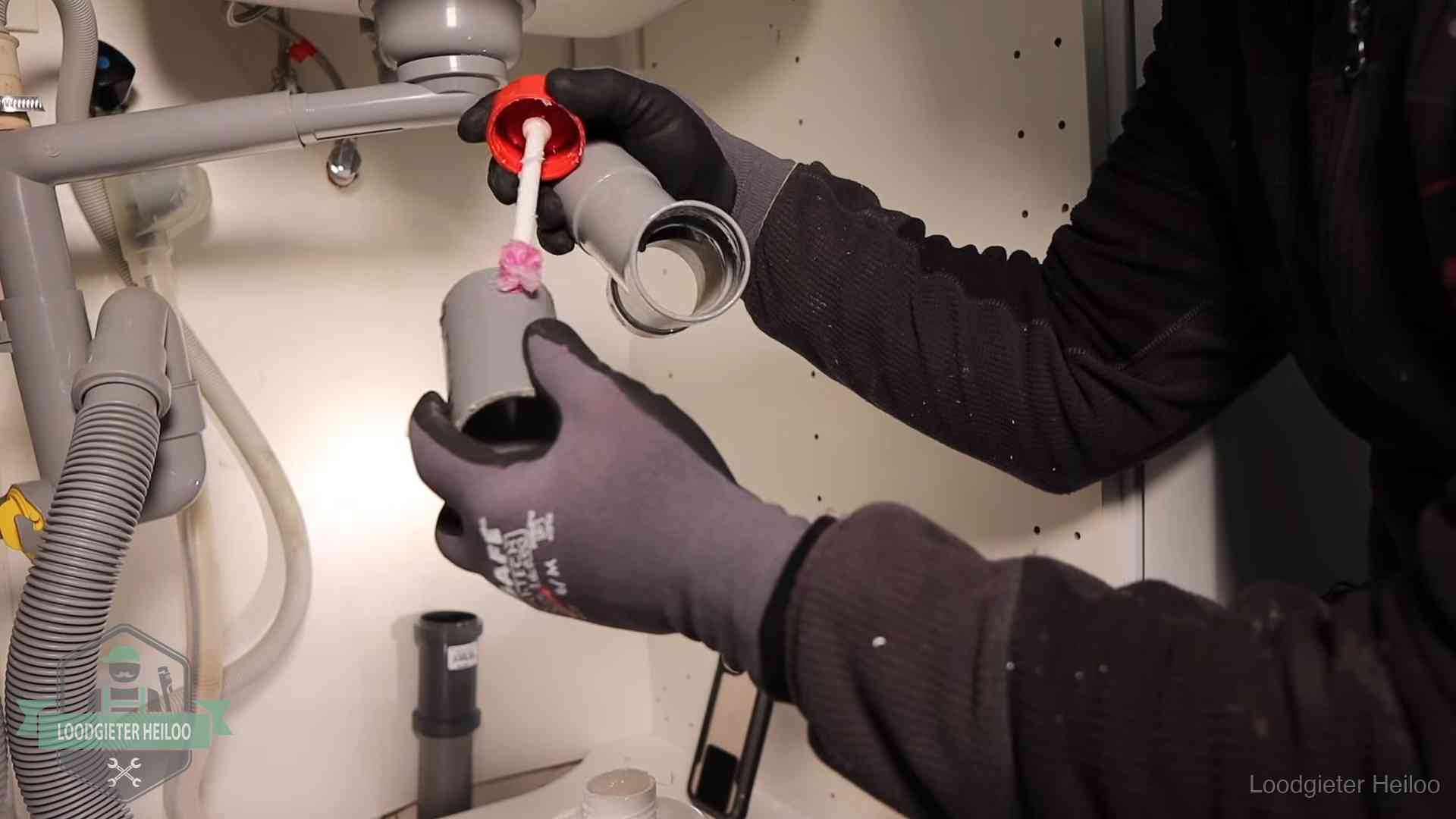 Loodgieter demonteert en reinigt de sifon onder een keukenkast in Heiloo