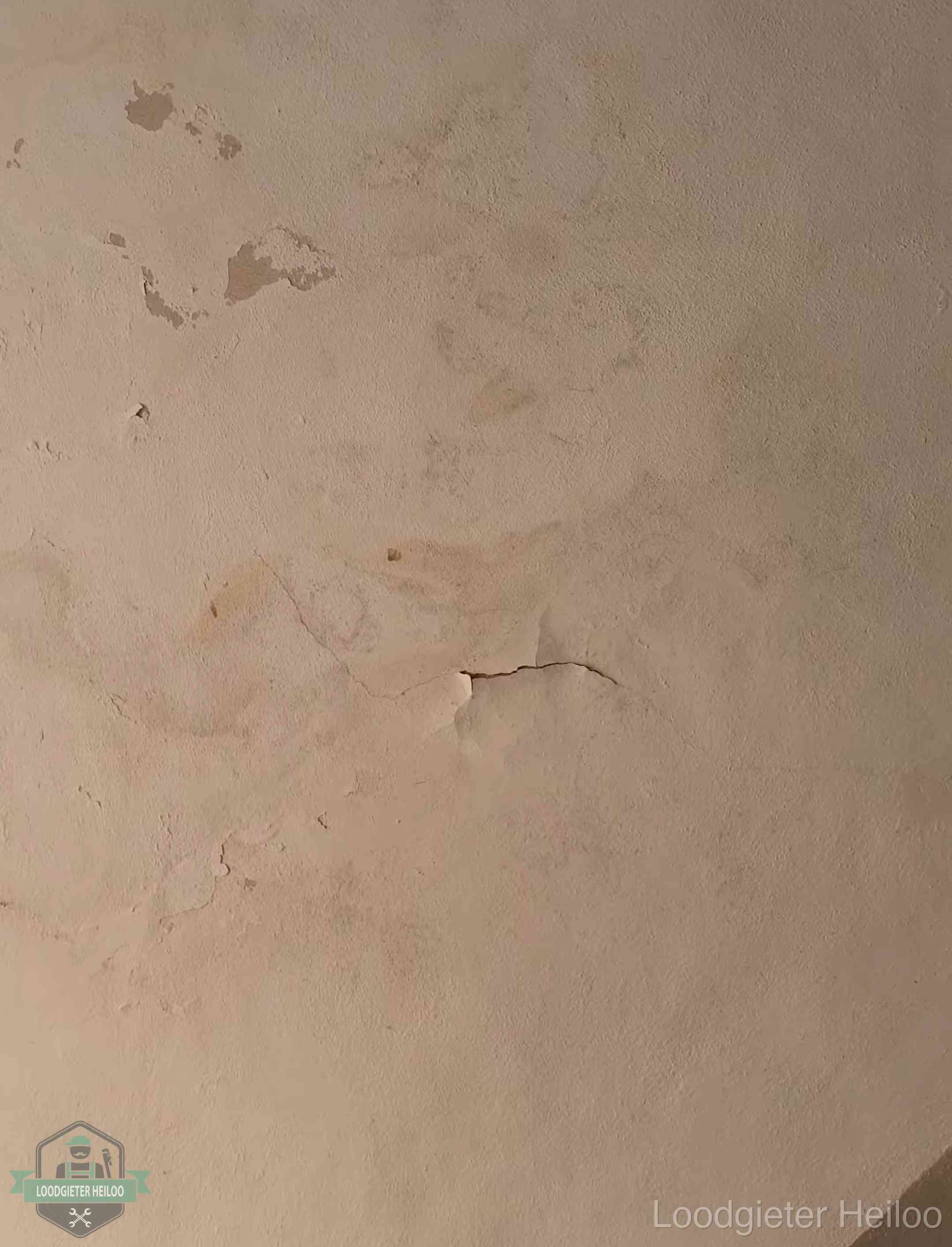 Vochtkringen en afbladderende verf op een plafond in Heiloo, schade voor het meetrapport en de verzekering